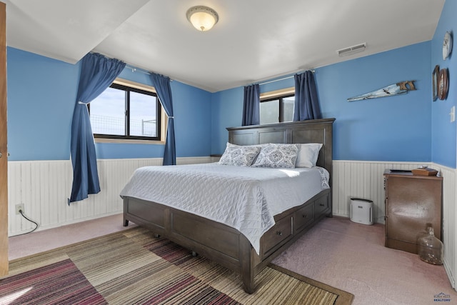 bedroom featuring carpet floors, a wainscoted wall, and visible vents