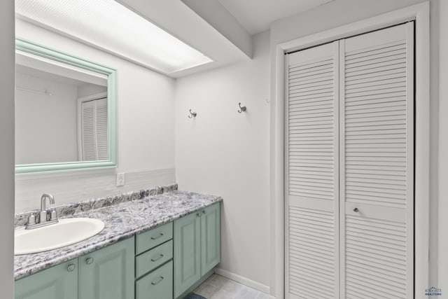 bathroom featuring baseboards, a closet, and vanity