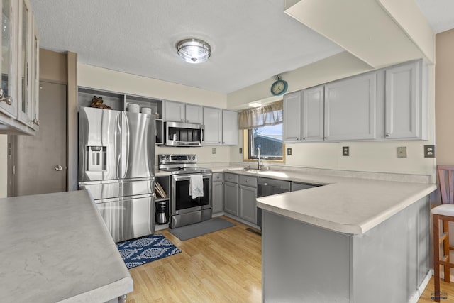 kitchen with light wood-style flooring, stainless steel appliances, light countertops, and gray cabinetry