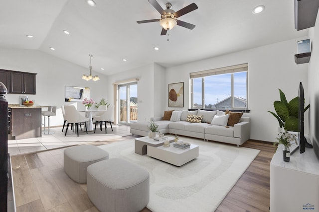 living area with a healthy amount of sunlight, light wood-type flooring, and vaulted ceiling