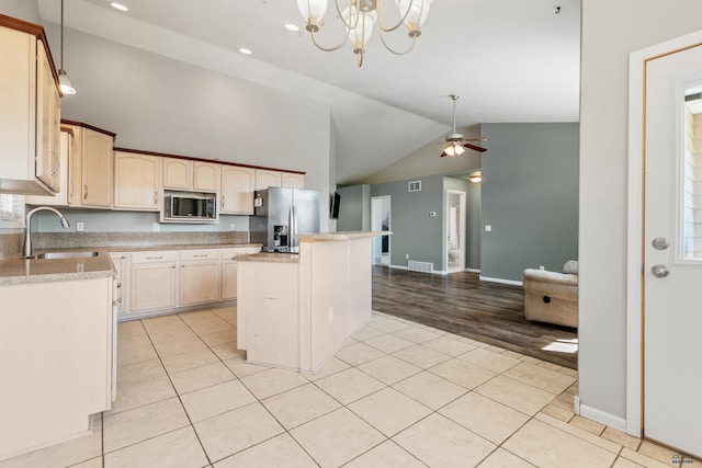 kitchen featuring light tile patterned flooring, light countertops, stainless steel appliances, a sink, and ceiling fan with notable chandelier