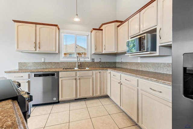 kitchen featuring decorative light fixtures, stainless steel appliances, light tile patterned flooring, a sink, and light brown cabinets