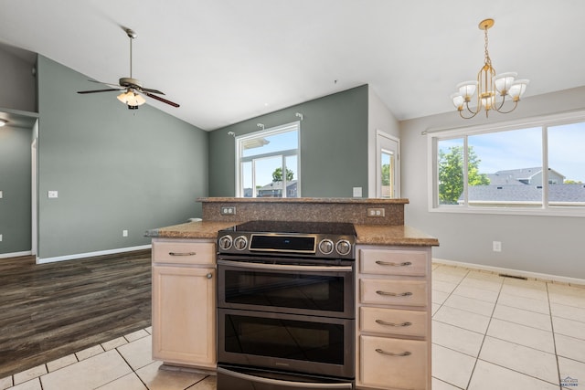 kitchen featuring range with two ovens, lofted ceiling, light tile patterned flooring, and light brown cabinetry