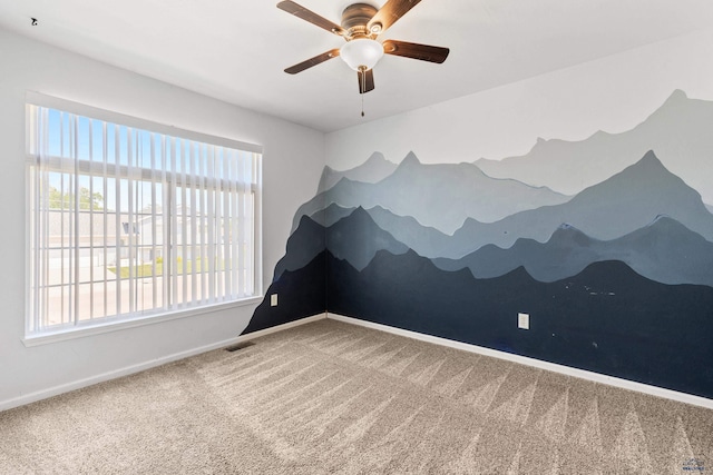 empty room featuring carpet floors, baseboards, visible vents, and ceiling fan