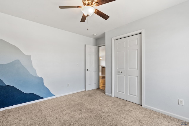 unfurnished bedroom with a closet, carpet, a ceiling fan, and baseboards