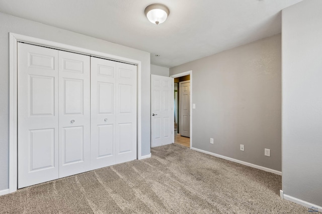 unfurnished bedroom with a closet, carpet flooring, and baseboards