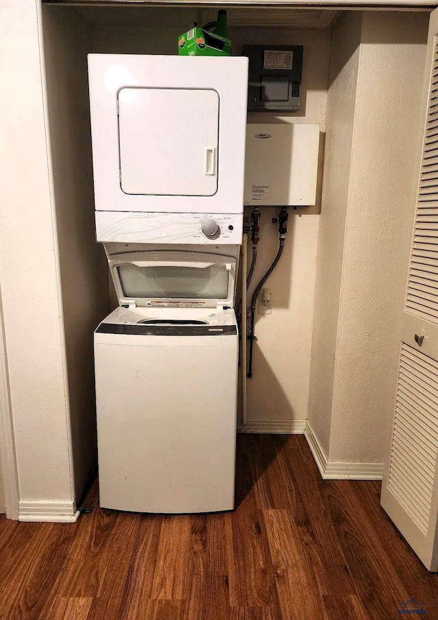 clothes washing area with laundry area, baseboards, dark wood finished floors, and stacked washer and clothes dryer