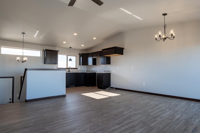 kitchen with a sink, baseboards, vaulted ceiling, dark wood-style floors, and decorative light fixtures