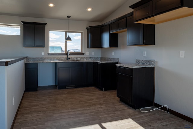 kitchen with wood finished floors, vaulted ceiling, a sink, and recessed lighting