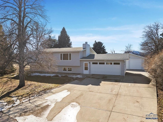 tri-level home with a chimney and an attached garage