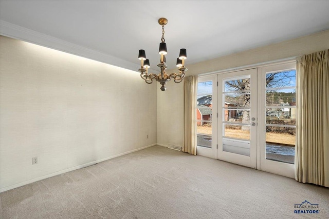 empty room with carpet, crown molding, a notable chandelier, and french doors