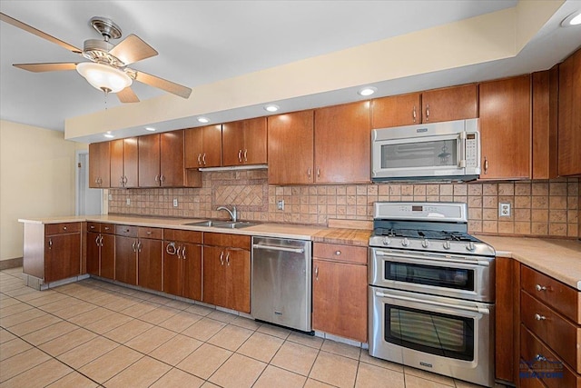 kitchen featuring appliances with stainless steel finishes, light countertops, a sink, and light tile patterned flooring