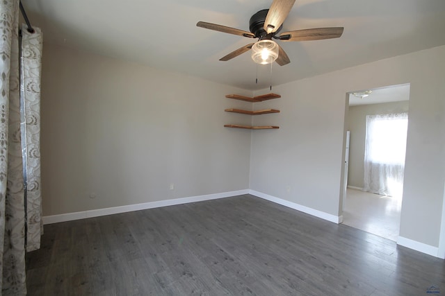 empty room featuring ceiling fan, dark wood-type flooring, and baseboards