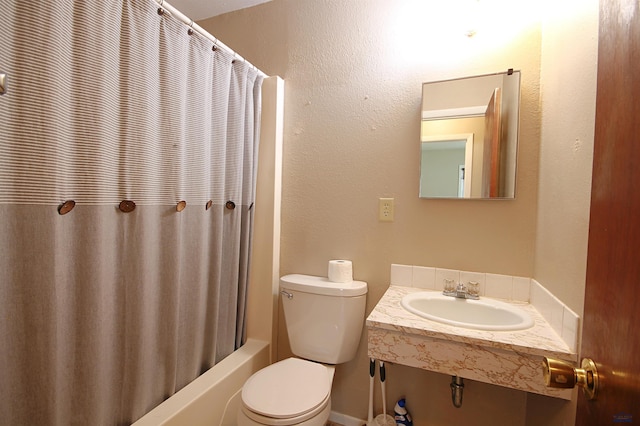 bathroom featuring toilet, shower / bath combo with shower curtain, a sink, and a textured wall