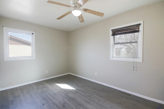 empty room with ceiling fan, wood finished floors, visible vents, and baseboards