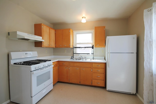 kitchen featuring light countertops, a sink, white appliances, under cabinet range hood, and baseboards