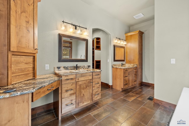 full bathroom featuring two vanities, a sink, visible vents, and baseboards