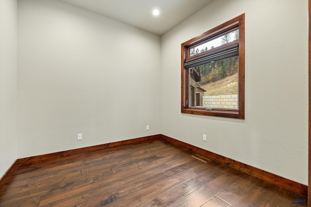 unfurnished room featuring dark wood-style floors and baseboards