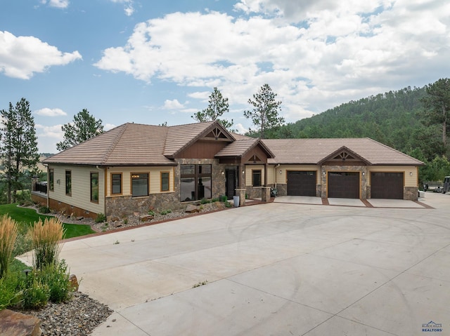 view of front of home featuring stone siding, an attached garage, a tile roof, and driveway