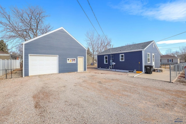 exterior space with a garage, driveway, fence, and an outdoor structure