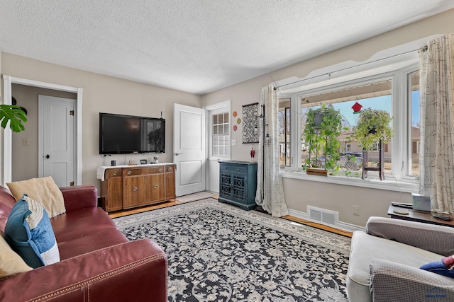 living room featuring baseboards, visible vents, and a textured ceiling