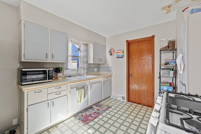 kitchen with light floors, light countertops, visible vents, a sink, and white range with gas cooktop