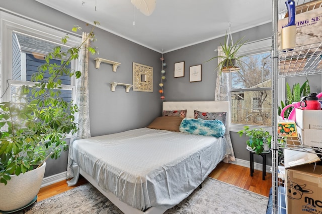 bedroom with crown molding, baseboards, and wood finished floors