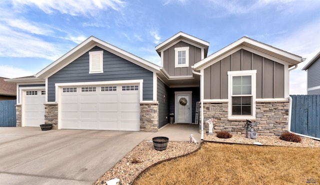 craftsman house featuring an attached garage, fence, driveway, stone siding, and board and batten siding