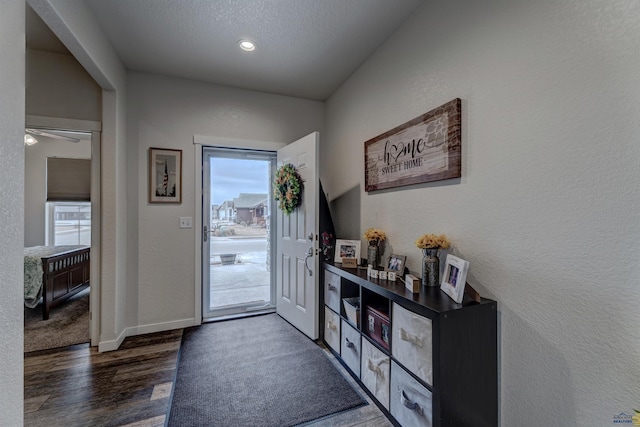 entryway with a textured ceiling, baseboards, wood finished floors, and a textured wall