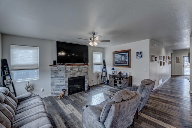 living area featuring a textured ceiling, a fireplace, wood finished floors, a ceiling fan, and baseboards