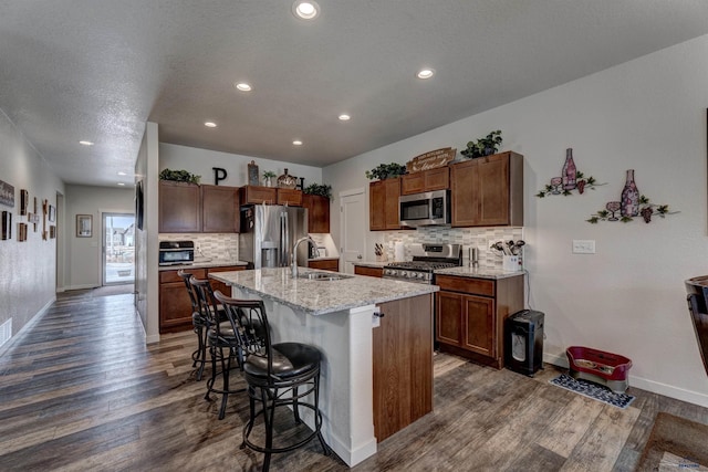 kitchen with tasteful backsplash, a breakfast bar area, dark wood-style flooring, stainless steel appliances, and a sink