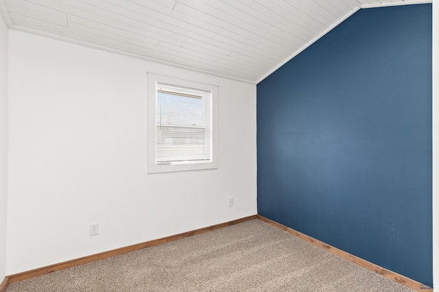 carpeted spare room with vaulted ceiling and baseboards