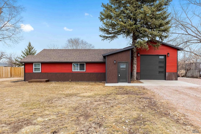 view of front of home with a garage, dirt driveway, fence, and roof with shingles