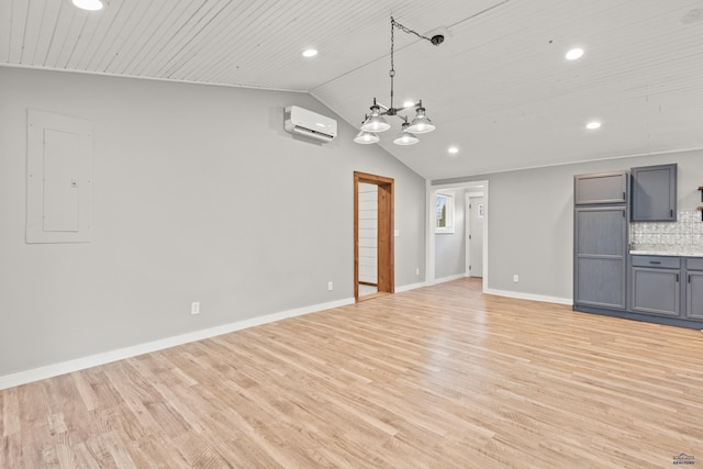 unfurnished living room with light wood-style floors, an AC wall unit, vaulted ceiling, electric panel, and baseboards