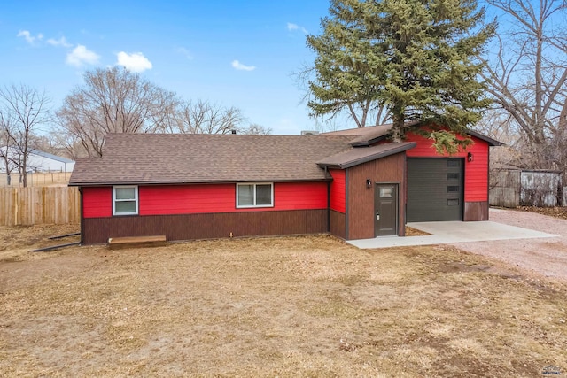 view of front of house featuring a patio, a garage, a shingled roof, fence, and driveway