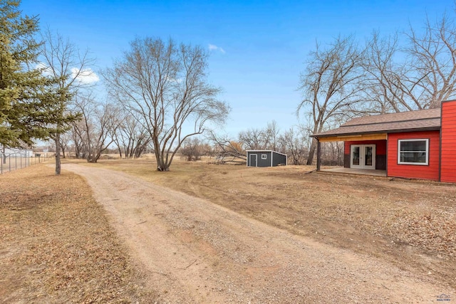 view of yard featuring a shed, fence, an outdoor structure, and french doors