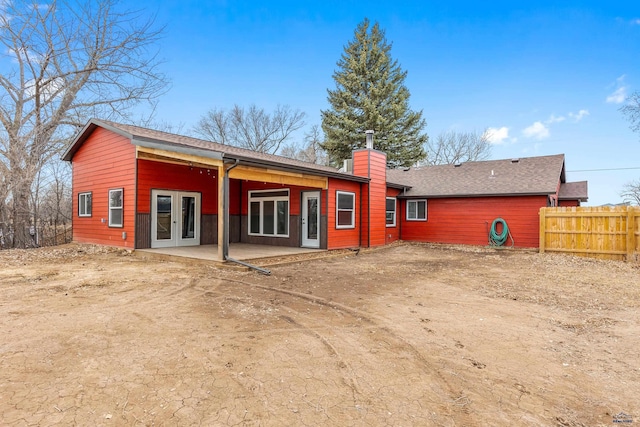 back of property with french doors, a chimney, a patio area, fence, and driveway