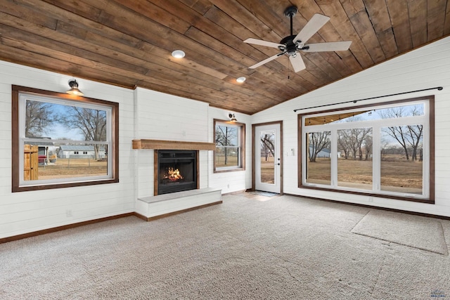 unfurnished living room with wood ceiling, vaulted ceiling, a wealth of natural light, and a lit fireplace