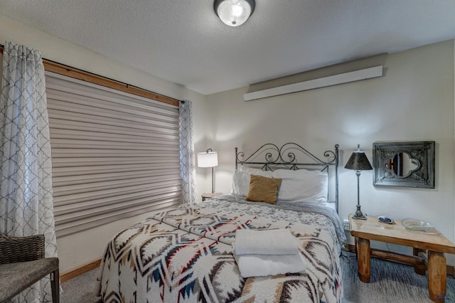 carpeted bedroom featuring a textured ceiling and baseboards