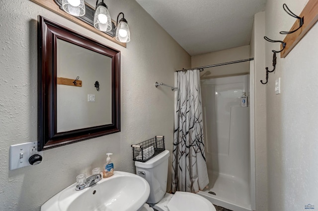 bathroom with toilet, a shower with curtain, a sink, and a textured wall