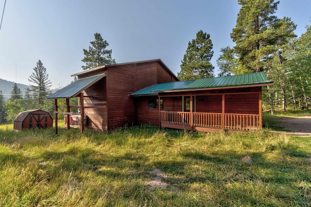 back of house with an outbuilding, metal roof, and a storage unit