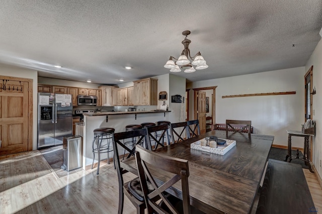 dining area with recessed lighting, light wood-style floors, a textured ceiling, a chandelier, and baseboards