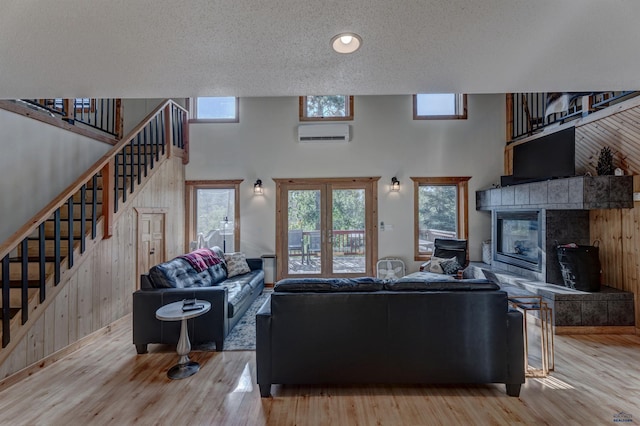 living area with a tile fireplace, stairway, wood finished floors, and a wall mounted air conditioner