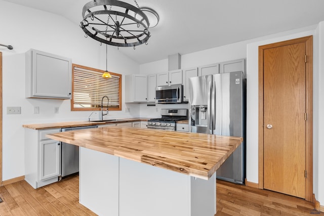 kitchen featuring light wood-style flooring, stainless steel appliances, a sink, wood counters, and vaulted ceiling