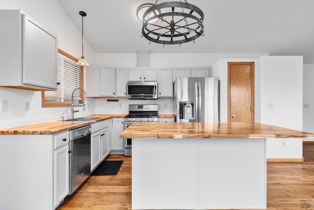 kitchen with light wood-style floors, appliances with stainless steel finishes, wooden counters, and a sink