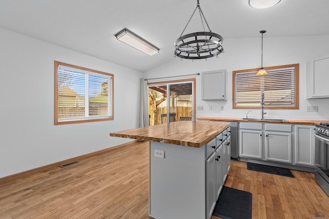 kitchen featuring visible vents, lofted ceiling, light wood-style flooring, wood counters, and a sink