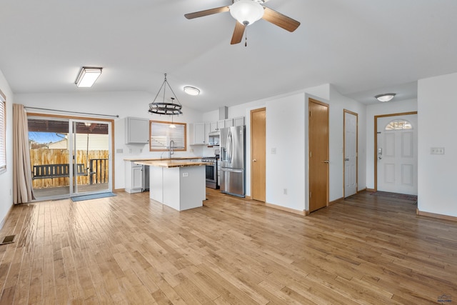 kitchen with a center island, stainless steel appliances, lofted ceiling, visible vents, and light wood-style flooring