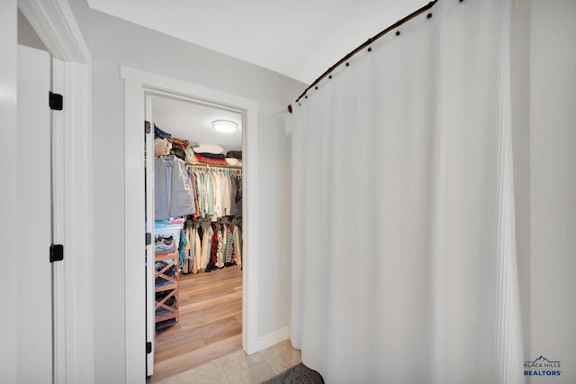 bathroom with a walk in closet and wood finished floors