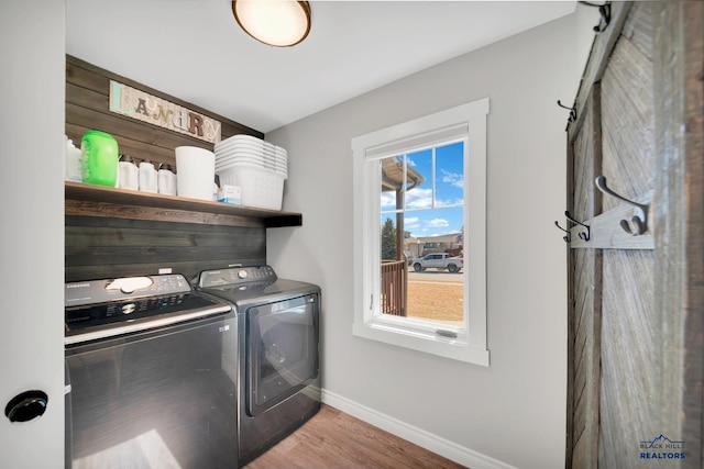 laundry room with laundry area, separate washer and dryer, wood finished floors, and baseboards