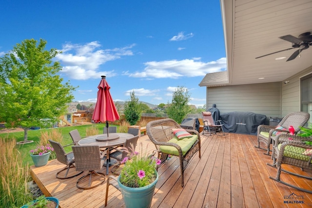 wooden deck with a ceiling fan, outdoor dining space, and grilling area